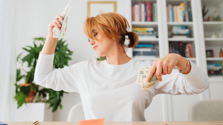 woman dancing at desk with cash in her hands