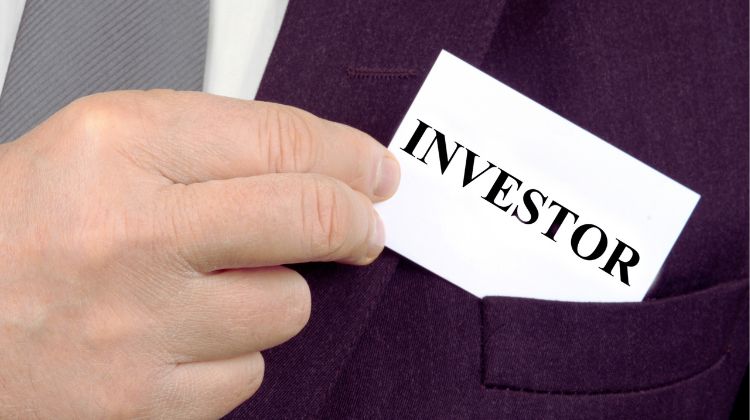 man in suit pulling out a business card that says "investor"
